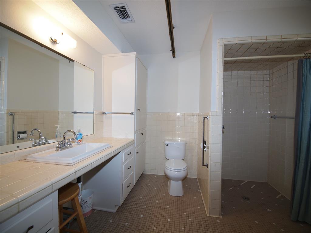 1441 Brazos Street Graham, TX 76450 - Photo 20 of 34 a bathroom with a granite countertop sink a toilet and a mirror