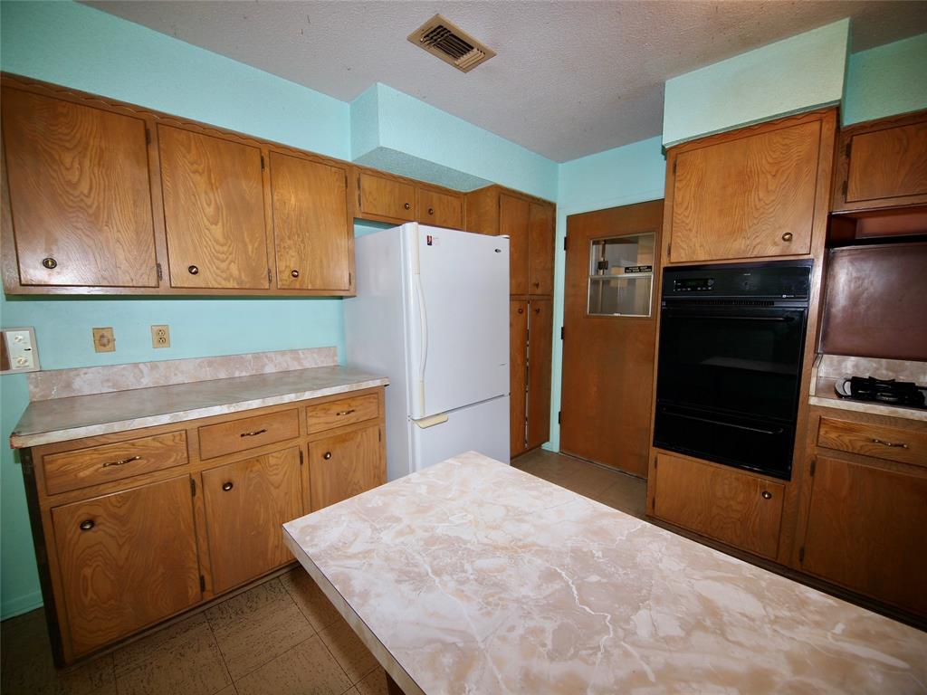 1441 Brazos Street Graham, TX 76450 - Photo 8 of 34 a kitchen with a refrigerator sink and cabinets
