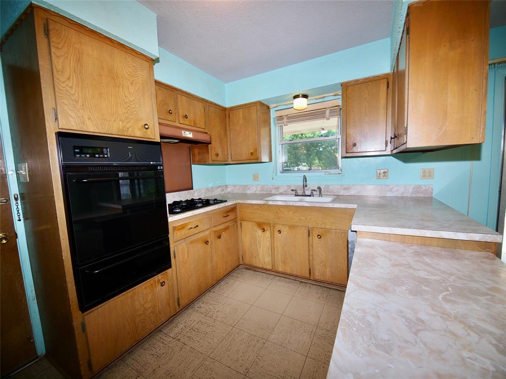 1441 Brazos Street Graham, TX 76450 - Photo 9 of 34 a kitchen with a sink stove and cabinets