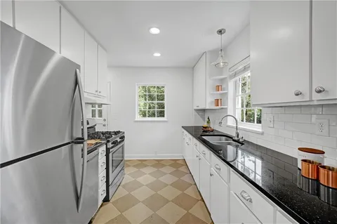 a kitchen with stainless steel appliances granite countertop a refrigerator a sink and white cabinets