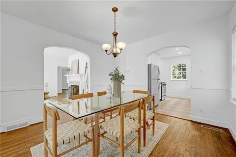 a dining room with wooden floor a chandelier a wooden table and chairs