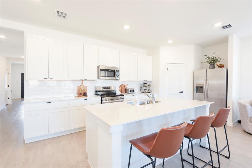 a kitchen with stainless steel appliances a sink a stove a refrigerator cabinets and a dining table