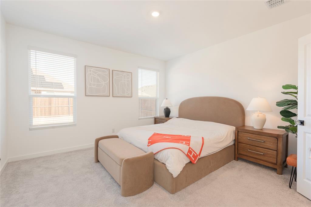 512 Capstone Court Princeton, TX 75407 - Photo 27 of 32 a bedroom with a bed lamp and a potted plant