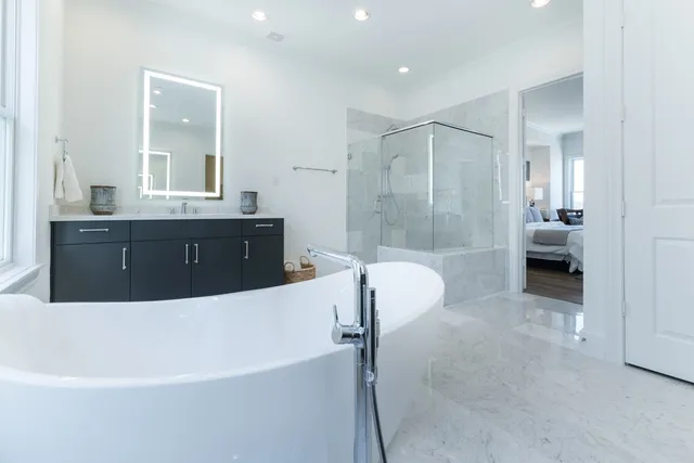 a spacious bathroom with a tub sink shower and mirror