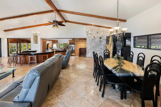 a kitchen with stainless steel appliances kitchen island granite countertop a table chairs in it and a window