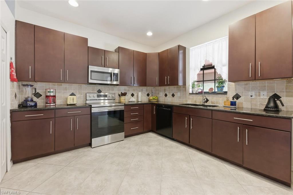 7577 Bristol Circle Naples, FL 34120 - Photo 11 of 41 a kitchen with a sink a stove and cabinets