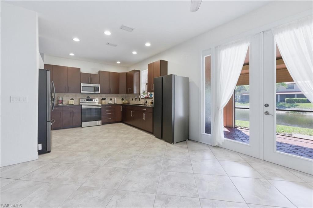 7577 Bristol Circle Naples, FL 34120 - Photo 14 of 41 a kitchen with stainless steel appliances granite countertop a refrigerator and a stove top oven