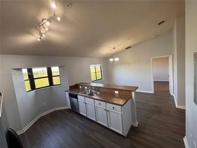 a large kitchen with stainless steel appliances a large counter top a stove a sink a refrigerator and a window