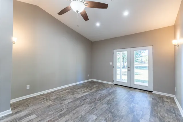 an empty room with wooden floor fan and windows