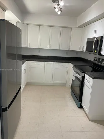 a kitchen with white cabinets and black appliances