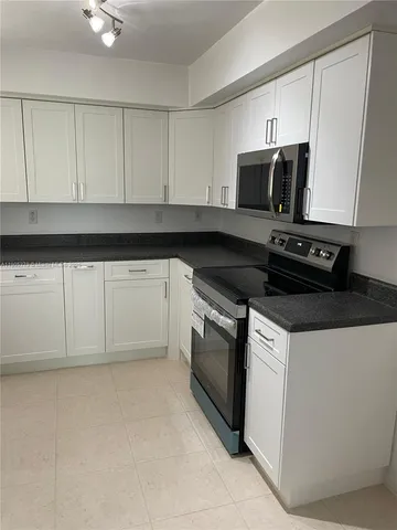 a kitchen with granite countertop white cabinets and black appliances