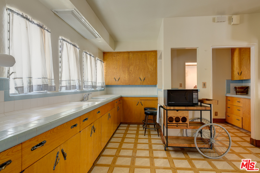 1003 Benedict Canyon Drive Beverly Hills, CA 90210 - Photo 12 of 35 a large kitchen with a table chairs and a sink