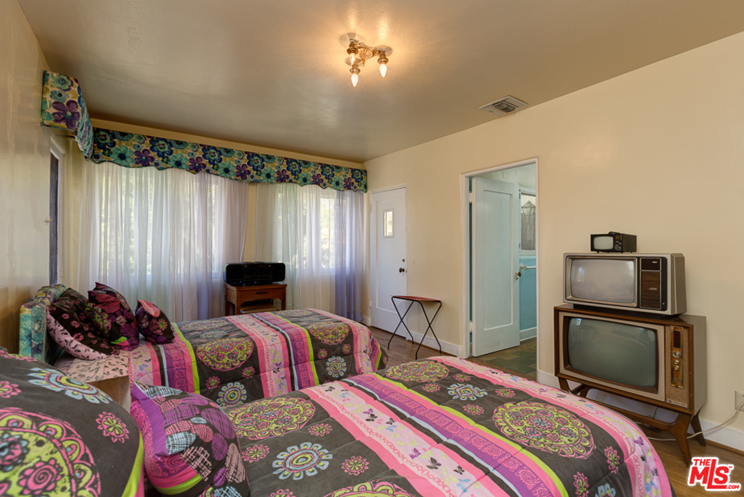 1003 Benedict Canyon Drive Beverly Hills, CA 90210 - Photo 23 of 35 a bedroom with a bed and a chandelier