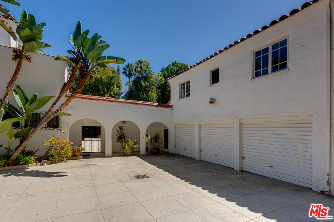 1003 Benedict Canyon Drive Beverly Hills, CA 90210 - Photo 28 of 35 a view of a white house with a yard and potted plants