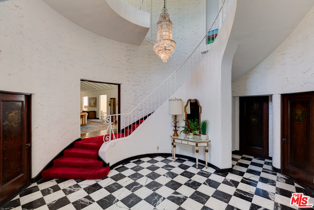 1003 Benedict Canyon Drive Beverly Hills, CA 90210 - Photo 4 of 35 a bedroom with a bed and a chandelier