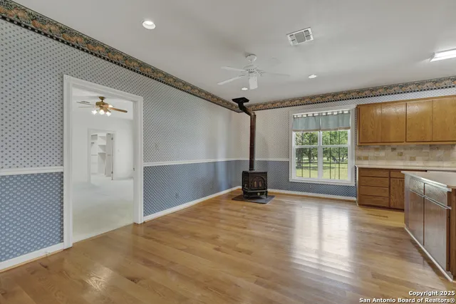 a view of an empty room with window and wooden floor