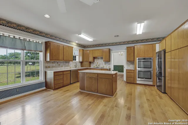 a large kitchen with a large window and stainless steel appliances