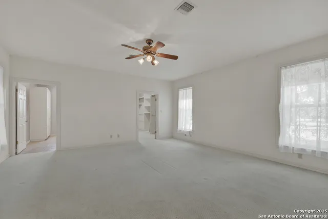 an empty room with windows and ceiling fan
