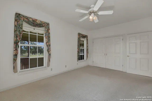an empty room with windows and ceiling fan