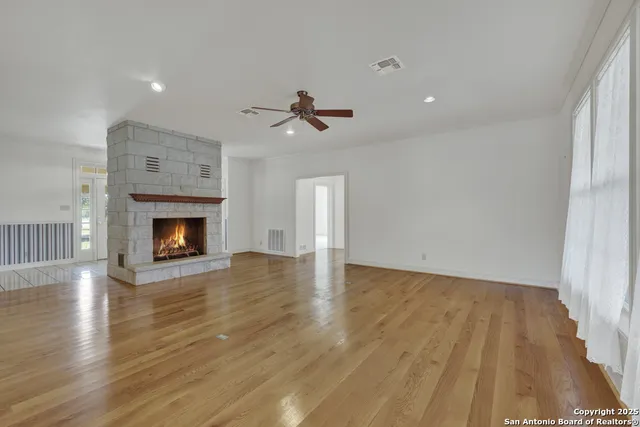 an empty room with wooden floor fireplace and a window