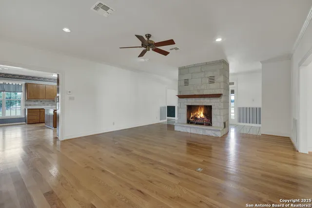 an empty room with wooden floor fireplace and windows