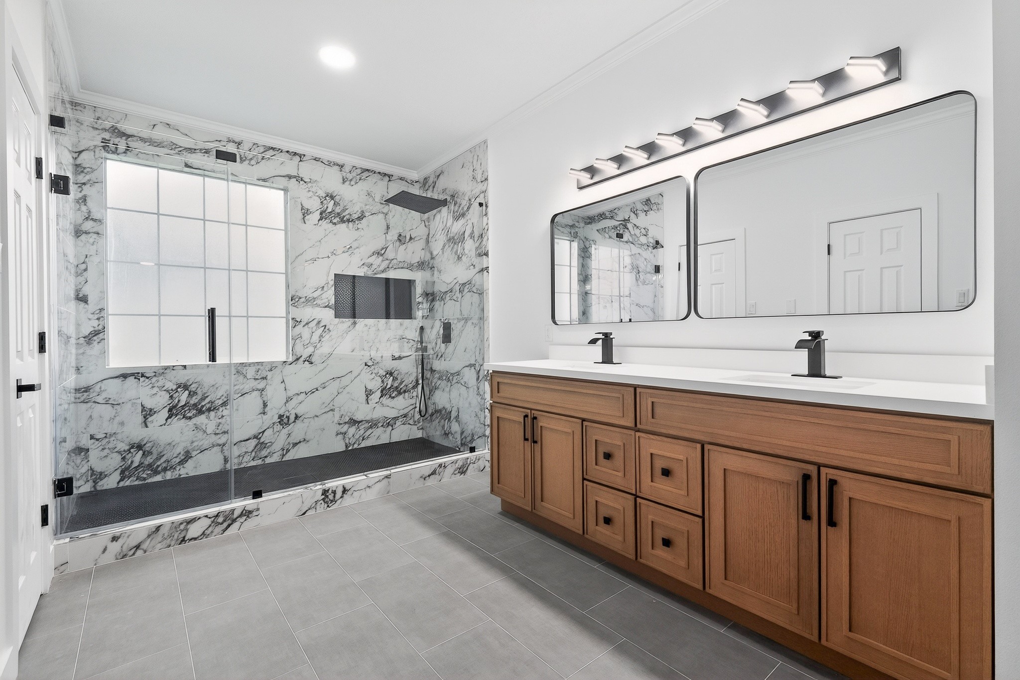 523 Rampart Lane Conroe, TX 77302 - Photo 18 of 41 Indulge in this fully renovated spa like primary bathroom showcasing a dramatic marble look shower, frameless glass enclosure, dual quartz vanities, custom cabinetry, and elegant details.