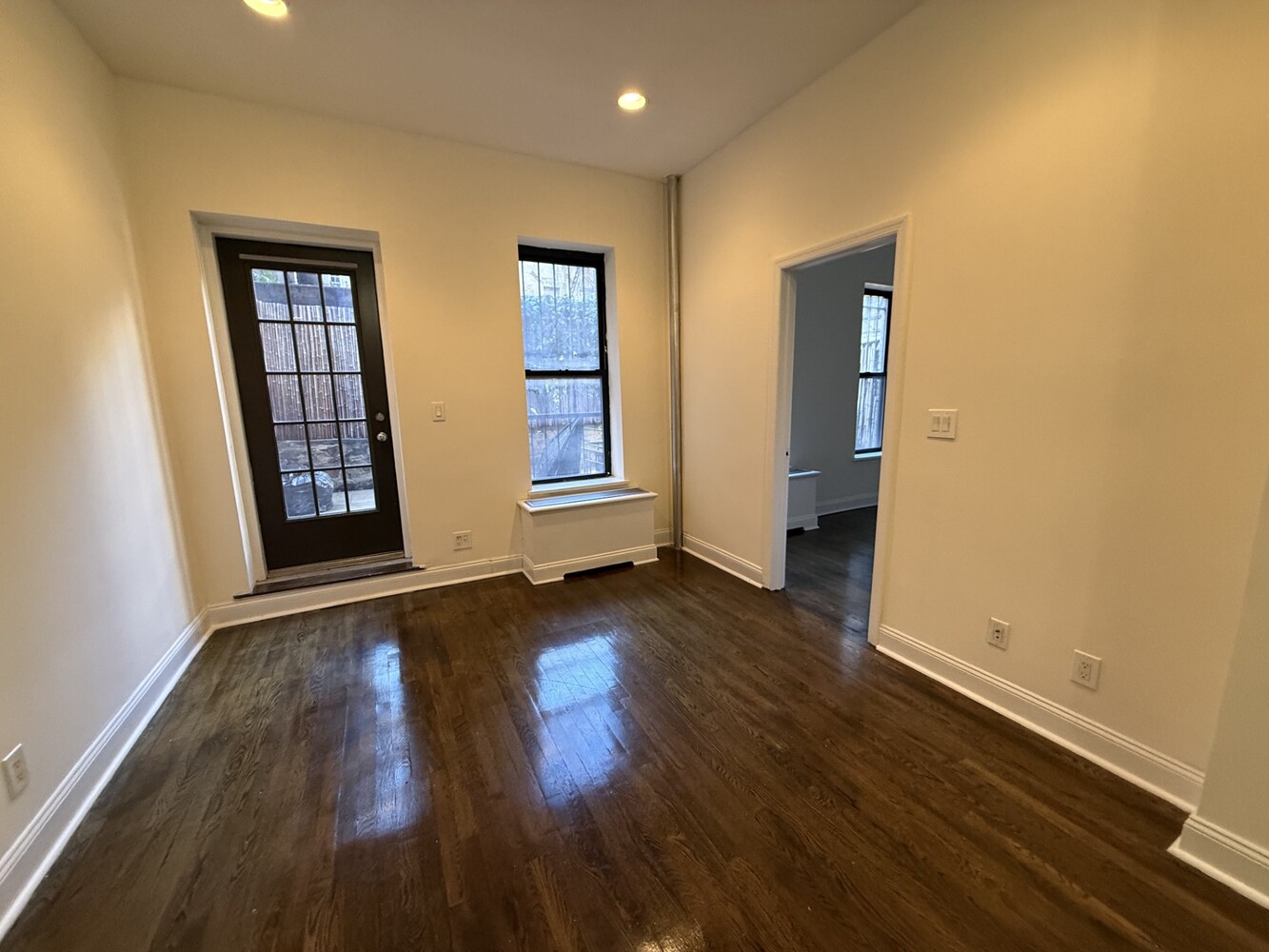 73 Thompson Street, Unit 1A Manhattan, NY 10012 - Photo 2 of 6 an empty room with wooden floor and windows