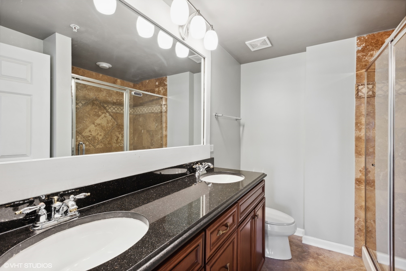 701 West Rand Road, Unit 330 Arlington Heights, IL 60004 - Photo 10 of 16 a bathroom with a granite countertop sink a toilet a mirror and shower