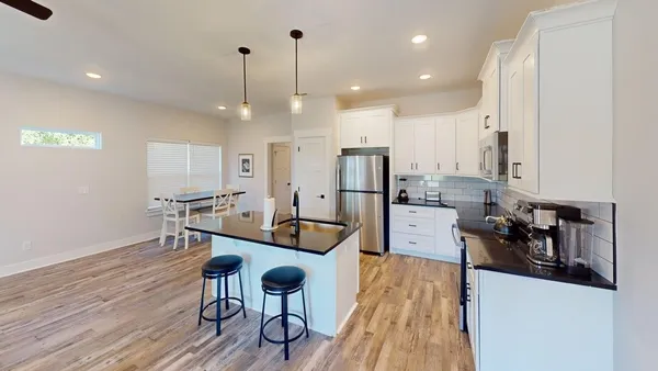 a kitchen with stainless steel appliances kitchen island granite countertop a table chairs stove and a wooden floors