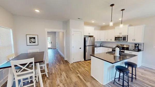 a kitchen with stainless steel appliances granite countertop a refrigerator a stove a sink dishwasher and white cabinets with wooden floor