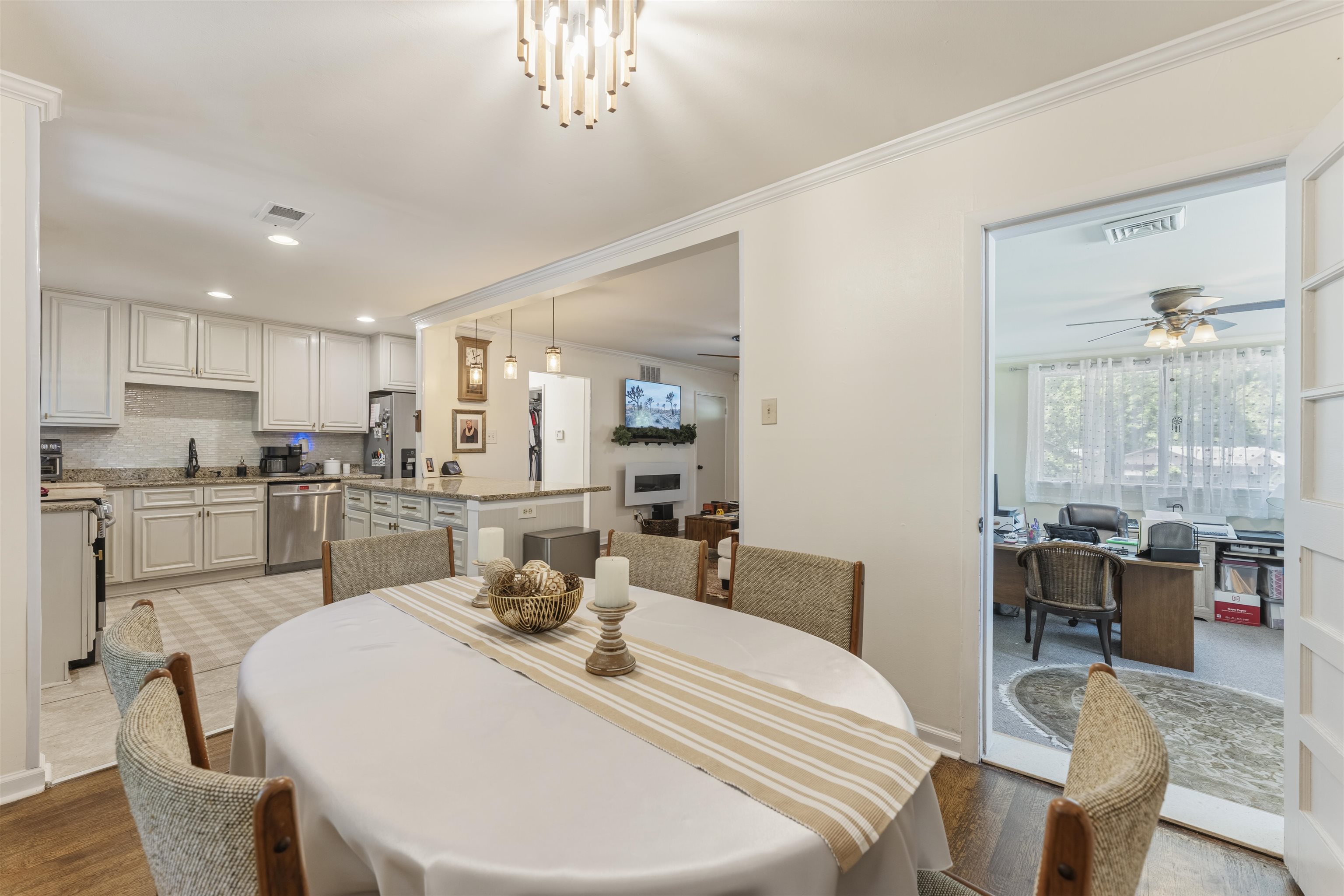 5271 Princeton Road Memphis, TN 38120 - Photo 26 of 30 Dining area with a contemporary chandelier, hardwood flooring, and direct access to a kitchen featuring light cabinetry, stainless steel appliances, and a tiled backsplash