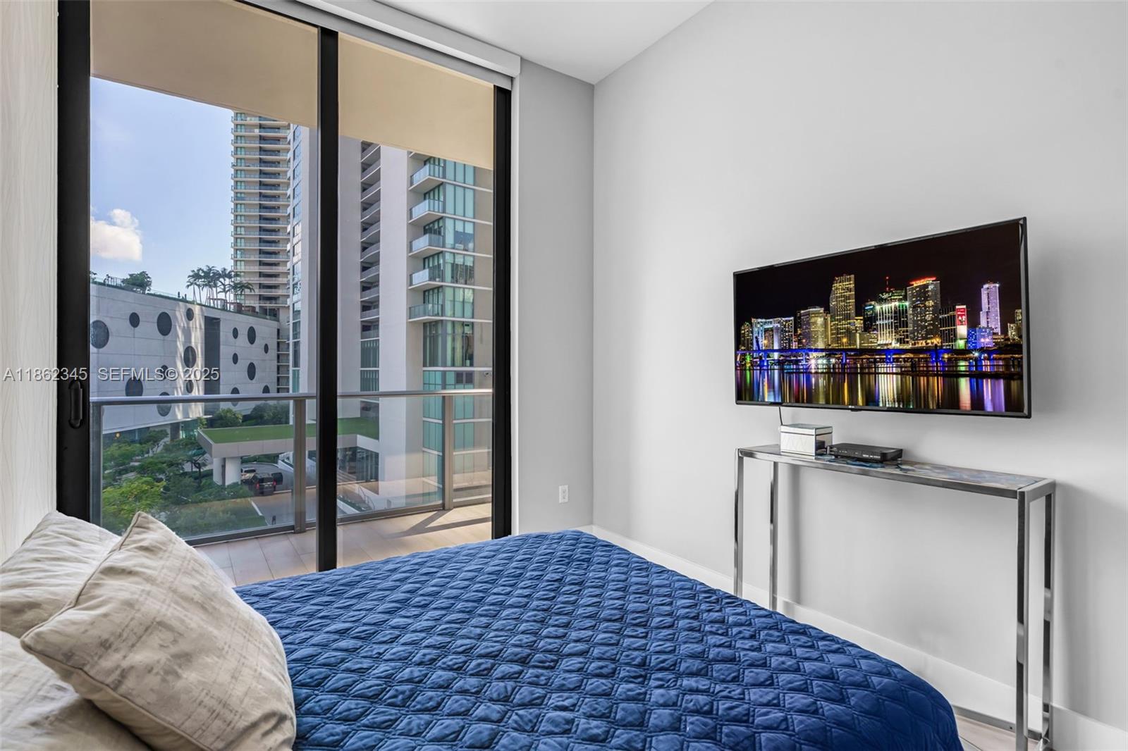 501 Northeast 31st Street, Unit 306 Miami, FL 33137 - Photo 21 of 65 a bedroom with a bed window and a flat screen tv