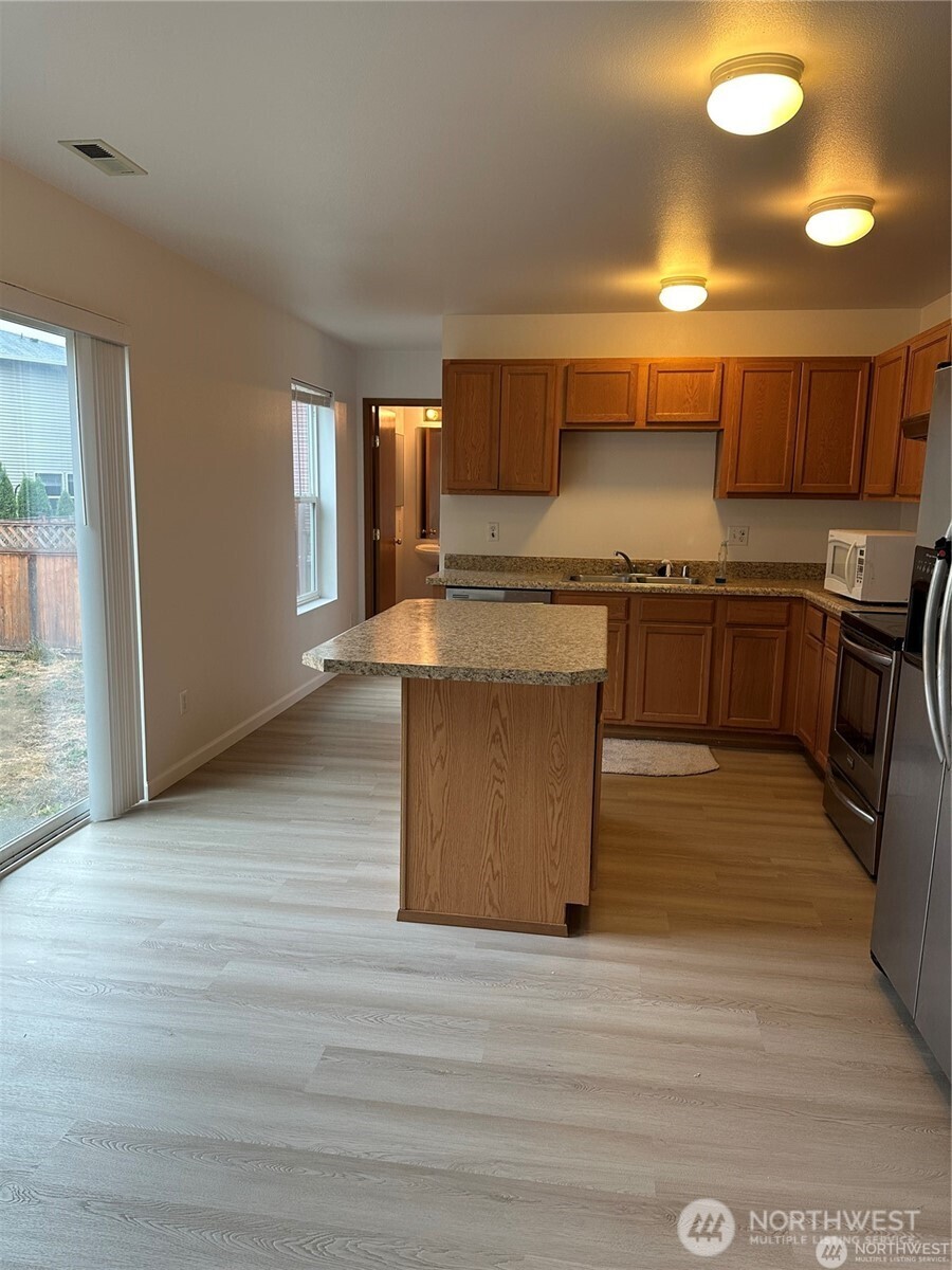 19114 14th Drive Southeast Bothell, WA 98012 - Photo 7 of 13 a kitchen with stainless steel appliances granite countertop a stove top oven a sink dishwasher and a refrigerator with wooden floor