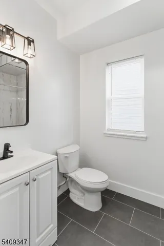 a bathroom with a toilet sink vanity and mirror