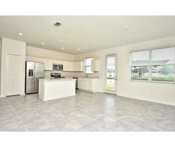 a view of kitchen with stainless steel appliances kitchen island a refrigerator sink and cabinets