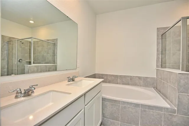 a bathroom with a granite countertop bathtub sink vanity and mirror