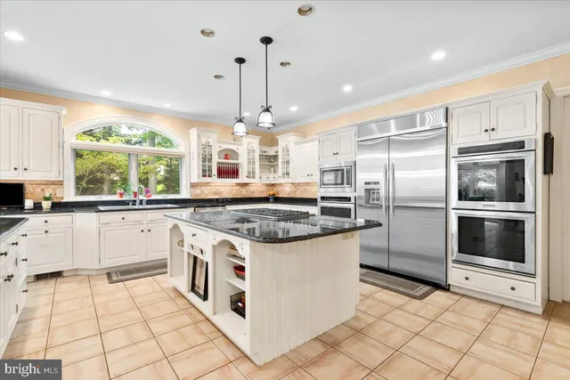 a large kitchen with stainless steel appliances granite countertop a stove and white cabinets