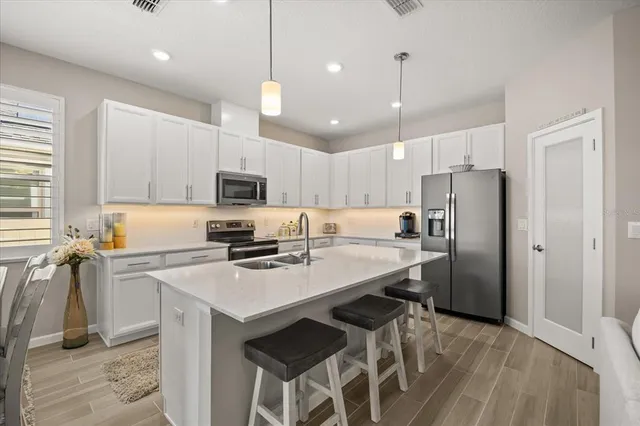 a kitchen with stainless steel appliances granite countertop a refrigerator a stove a sink dishwasher a oven with a dining table and chairs