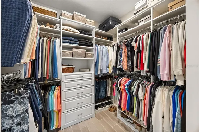a view of walk in closet with clothes and shoes