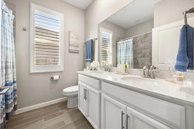 a bathroom with a double vanity sink toilet and a window