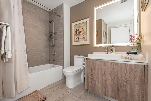 a bathroom with a sink a toilet a mirror a bathtub and shower