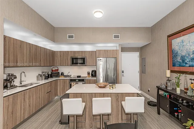 a kitchen with stainless steel appliances a dining table chairs and a refrigerator