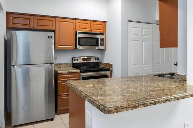 a kitchen with granite countertop a refrigerator stove and microwave