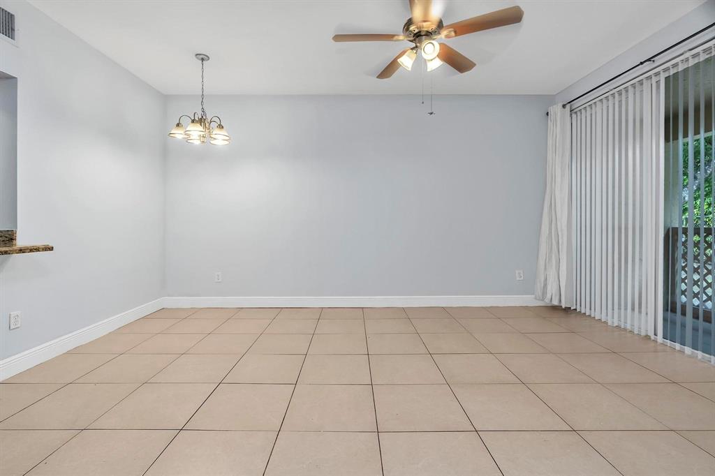 18352 Northwest 68th Avenue, Unit M Hialeah, FL 33015 - Photo 7 of 28 an empty room with chandelier fan and windows