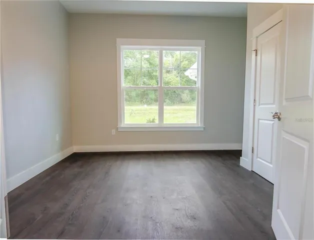 an empty room with wooden floor and window