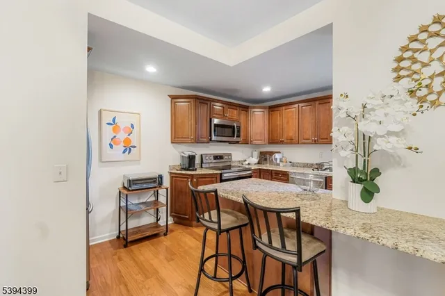 a kitchen with granite countertop stainless steel appliances a stove top oven a sink a dining table and chairs