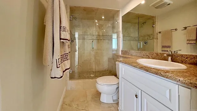 a bathroom with a granite countertop sink toilet and shower