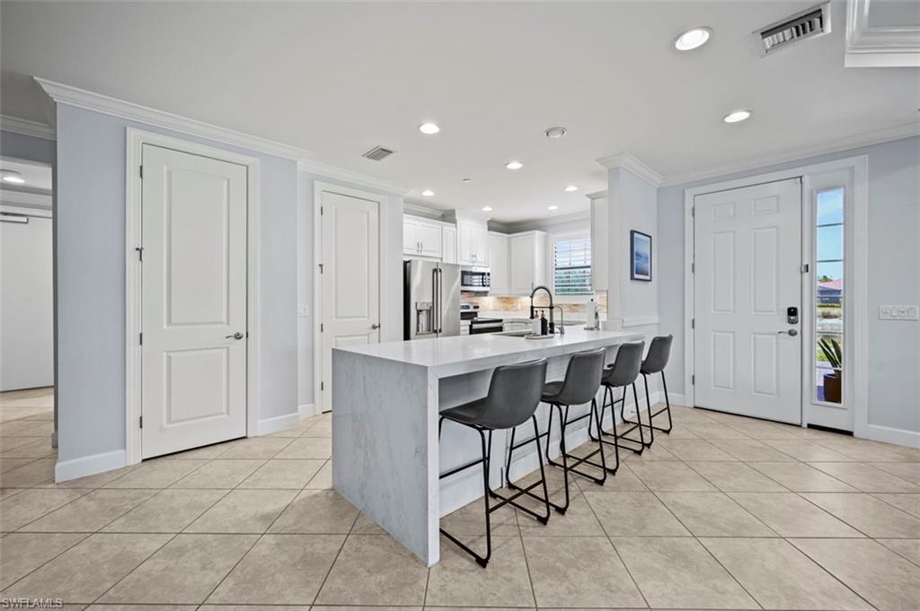 8777 Bellano Court, Unit 101 Naples, FL 34119 - Photo 6 of 39 a kitchen with stainless steel appliances kitchen island granite countertop a table and chairs in it