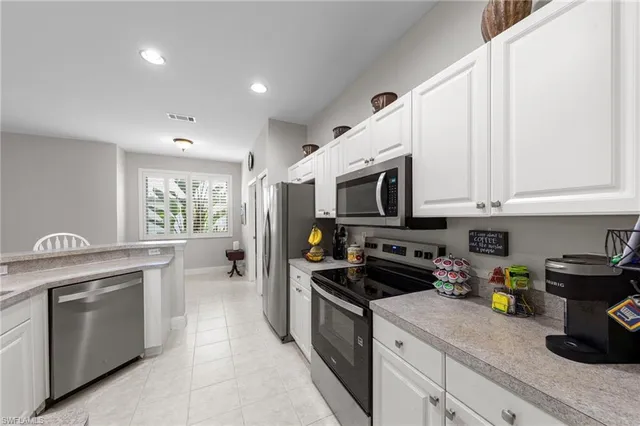 a kitchen with stainless steel appliances granite countertop white cabinets a stove a sink and a refrigerator