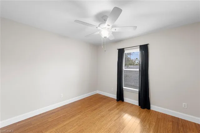 an empty room with wooden floor fan and windows